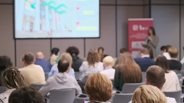 People attending a seminar in a conference room, actively listening to a speaker on stage.