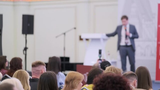 Conference presentation with audience focusing on speaker at podium in professional event setting.
