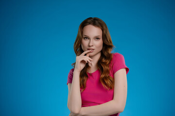Fototapeta premium Woman poses in a studio setting with a bright blue background, expressing emotion and confidence through her stance and expression