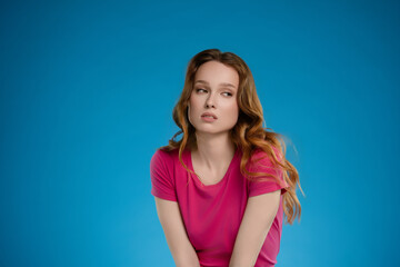 Woman posing in studio with emotional expression against a vibrant blue background
