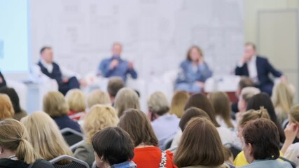 Audience gathered at a professional conference watching and listening to an expert panel discussion.