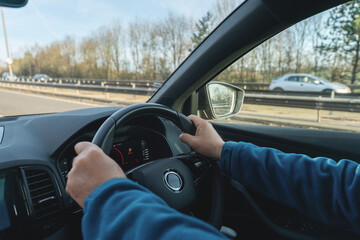 Man driving car with hands on stearing wheel
