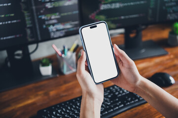 Young woman holding smartphone in modern office workspace with technology and computers showcasing programming and online work