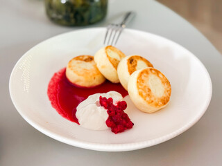 Syrniki served with sour cream and berry sauce. Traditional breakfast, rustic comfort and Eastern European cuisine