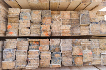 The wood is stacked, the wood is brown and has a rough texture. Lumber for construction and repair. Needles