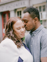 Couple enjoying an intimate moment in a charming urban setting during a sunny afternoon