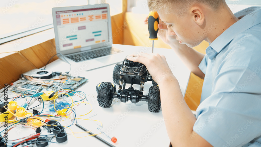 Poster top view of happy student study car model construction at table with electronic equipment and laptop