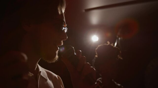 Low angle close-up shot of male and female stand-up artists performing together on dimly lit stage