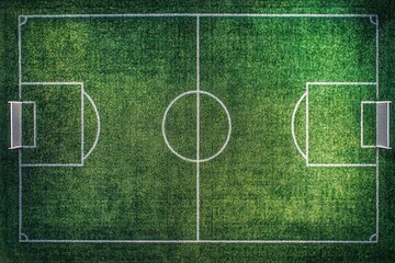 An aerial view of an empty green soccer field with white lines and goals