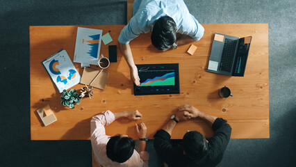 Naklejka premium Top aerial view of business man present financial graph to group of smart investors. Professional male leader analyze graph and explain marketing idea by using tablet on meeting table. Convocation.