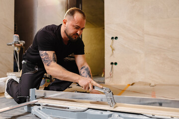 Construction Worker Cutting Ceramic Tile Using Tile Cutter in Bathroom