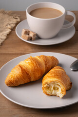 Freshly baked croissants served with a hot cup of coffee on a wooden table in a cozy setting