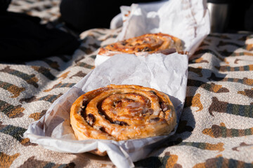 Freshly baked bun on paper wrap during picnic, warm golden crust, casual outdoor food scene in natural light