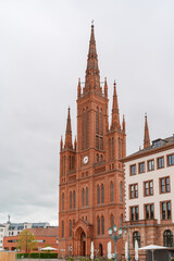 Fototapeta premium A large red building of Market church in Wiesbaden Germany with two tall spires and a clock tower