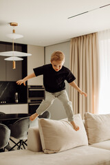 Obraz premium Happy child jumping on sofa in modern living room