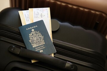 Canadian passport with tickets lies on touristic suitcase in airport hall