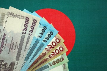 Bangladeshi taka money bills in big amount lies on Bangladesh flag close up