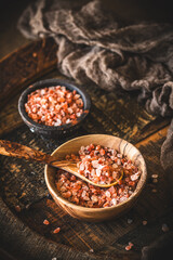 Himalayan salt in a wooden bowl on dark wooden background