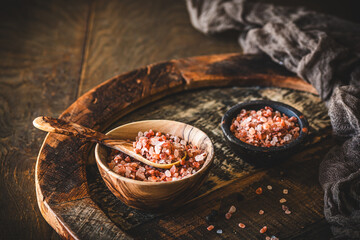 Himalayan salt in a wooden bowl on dark wooden background