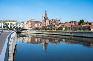 Naklejka premium The French city of Comines Hauts De France reflecting in the river Lys or Leie as seen in Comines - Warneton, Hainaut, Belgium