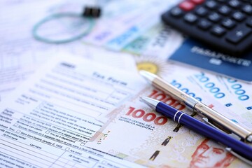 Argentine pesos money bills in big amount lies on table with pen, calculator, passport and tax forms