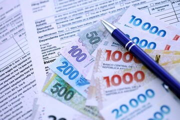 Argentine pesos money bills in big amount lies on table with pen and tax forms close up