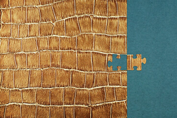 Puzzle piece with a crocodile leather texture fitting into a blue background. Concept of...