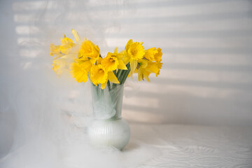 daffodil flowers stand on the table in a vase