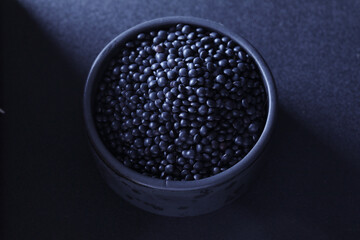Beluga black lentils. Bowl with black lentil on black background.