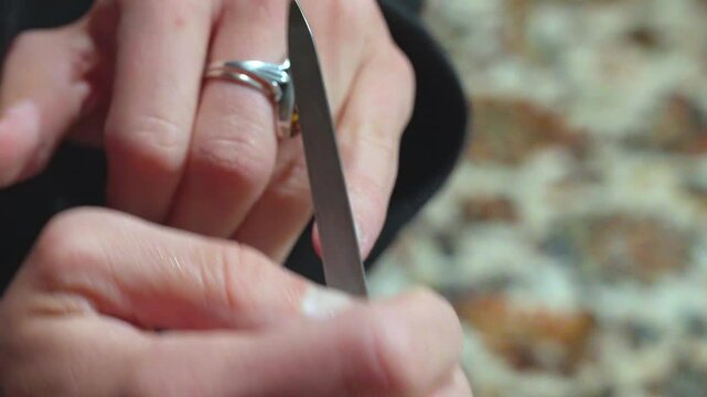 Woman's hands filing her nails on a carpet
