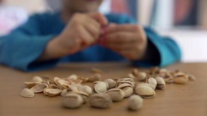 Child’s hands reaching for pistachio nuts on a table, focusing on the simple act of play and exploration