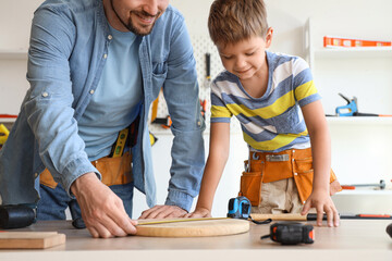 Happy father and his little son with different instruments assembling wooden furniture at home