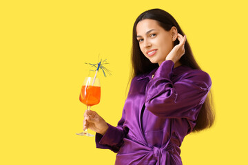 Young woman with aperol spritz cocktail on yellow background