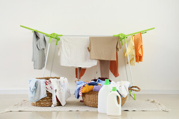 Dryer, laundry baskets and detergents near white wall