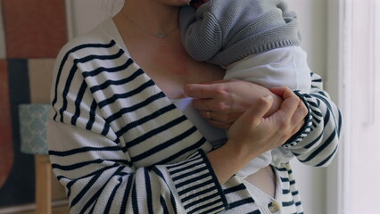 Close-up of mother holding newborn, hands gently cradling the baby’s head against her chest. the intimate, protective bond and the loving care provided to the newborn