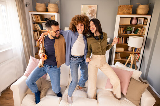 Three Friends Dancing Happily on a Couch in a Bright and Cheerful Living Space