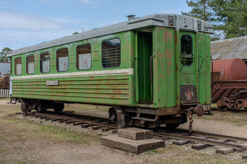 Green train car is parked on the tracks. The train car is old and rusty