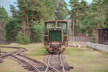 Green train car is parked on the tracks. The train car is old and rusty