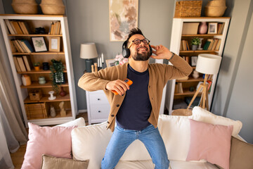 Man in Headphones Joyfully Rocks Out Playing Air Guitar in a Warm, Inviting Living Room