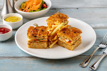 Square gourmet sandwiches with fries served on a white plate