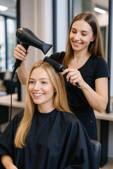 A hairdresser blow-drying a woman's hair in a modern salon.