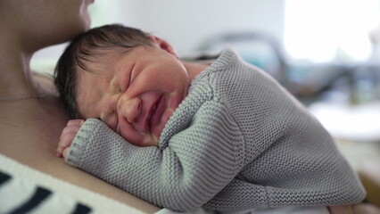 Newborn baby resting on mother's chest, visibly uncomfortable, expressing displeasure with a scrunched-up face. the tender moments of caring for a newborn in distress-SD 480p