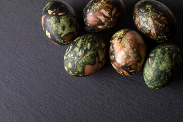 Easter decorations. Traditionally coloured Easter eggs on a black stone background. Top view, copy space.