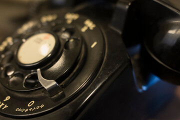 Close-up of a vintage rotary phone dial, showcasing its nostalgic black and silver design. Perfect for themes of communication, history, or retro technology.