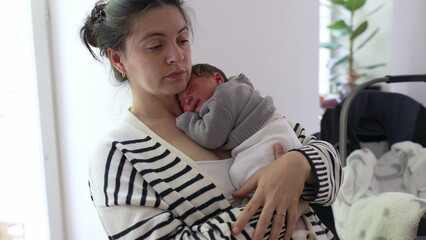 Mother holding sleeping newborn baby against her chest, conveying peacefulness and deep maternal...