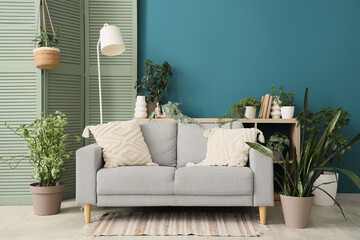 Sofa, lamp, folding screen and houseplants in interior of living room