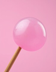 Shiny pink lollipop on stick against pastel background