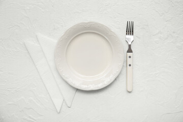 Plate with fork and paper napkins on white grunge background