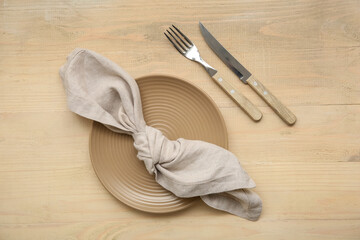 Plate with cutlery and napkin on wooden background