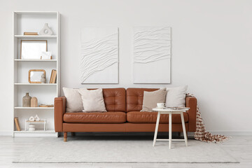 Brown leather sofa with white table and shelving unit in living room